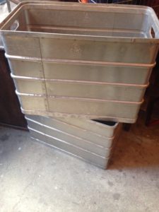Deux boîtes métalliques vintage empilées en diagonale les unes sur les autres dans un atelier avec sol en béton.