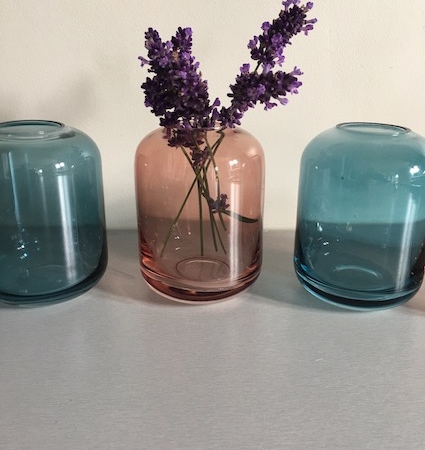 Trois vases en verre Soliflore Verre Coloré, deux bleus et un rose, avec des brins de lavande dans le vase rose, disposés sur une surface claire. Brocante 93