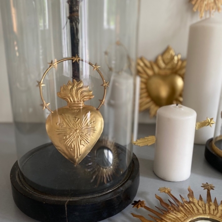 Le Coeur Auréole Or, enfermé dans un dôme de verre et entouré de bougies blanches et d'ornements de miroir en forme de soleil vintage, évoque une charmante esthétique rétro. Brocante 93