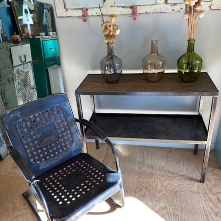 Une chaise noire antique, une table en bois ornée de vases en verre de fleurs séchées, entourée d'un décor rustique et des casiers rétro Desserte Industrielle 1960 VENDU, créent une charmante ambiance vintage qui rappelle la brocante 93. Brocante 93