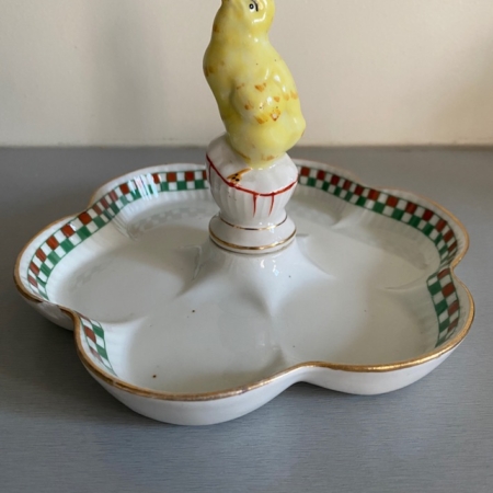 Un plat vintage en céramique blanche connu sous le nom de « Ramequin Oiseau 1950 Vendu », doté d'un bord à carreaux verts et rouges et d'une charmante figurine d'oiseau jaune au centre, parfait pour ajouter une touche de charme rétro à votre décoration intérieure. Brocante 93