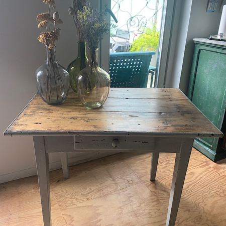 Une Table en Bois 1960 VENDU dans une pièce avec trois vases en verre contenant des fleurs séchées, près d'une fenêtre et d'une armoire verte vintage. Brocante 93