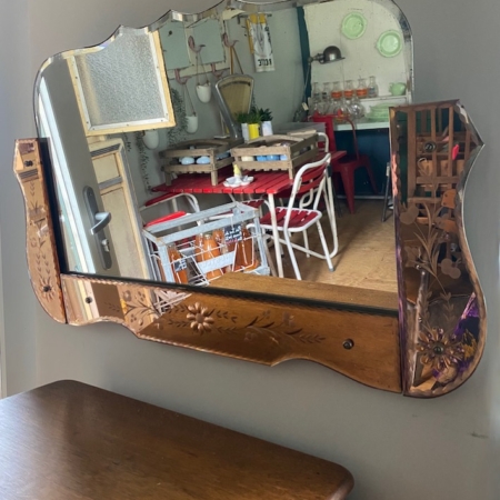 Un Miroir Bicolore 1950 VENDU reflète une cuisine chaleureuse avec des chaises rouges, une table en bois et des étagères ornées de contenants en verre. Brocante 93