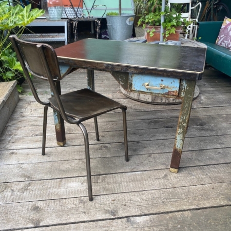 Le Bureau administratif 1940 sur la terrasse en bois rustique, entouré de plantes et de mobilier extérieur, évoque une charmante ambiance rétro. Brocante 93