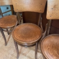 Trois Chaises Américaines 1940 aux motifs sculptés sur les assises et les dossiers sont disposées sur un parquet en bois.