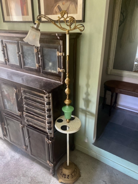 Un lampadaire américain 1930 aux détails complexes se dresse à côté d'une armoire ancienne dans une pièce aux murs verts et au sol recouvert de moquette, dégageant un charme rétro. Brocante 93