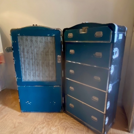 Deux malles de rangement Malle Cabine Américaine XIXème siècle bleues vintage se dressent ouvertes sur un plancher en bois, révélant un espace placard et de multiples tiroirs rappelant les modèles de malle du 19ème siècle. Brocante 93