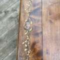 Table à rabats 1940, fabriquée en bois et ornée d'un motif floral complexe peint sur le coin, comportant des feuilles et des fleurs rappelant les motifs classiques de rabat. Brocante 93