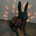 Le Photophore Lapin est une lanterne en céramique conçue avec des trous qui laissent passer la lumière, créant des motifs enchanteurs sur le mur et le sol. Brocante 93