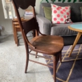 Dans un salon cosy, la Chaise de Bureau Américaine 1930 avec sa finition bois rustique sublime le canapé gris et les coussins colorés, créant une ambiance chaleureuse. Brocante 93