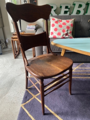 Une chaise de bureau américaine des années 1930 repose gracieusement sur un tapis violet près d'une table basse, avec un canapé et un coussin à pois en arrière-plan, ajoutant une touche de charme américain classique. Brocante 93