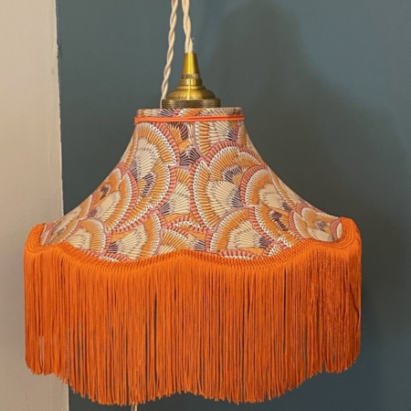 La Baladeuse Graphique, un abat-jour suspendu vintage à franges orange et tissu à motifs, complète joliment le mur bicolore avec son design chic. Brocante 93