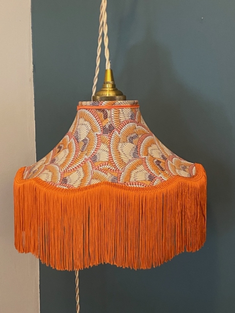 La Baladeuse Graphique, un abat-jour suspendu vintage à franges orange et tissu à motifs, complète joliment le mur bicolore avec son design chic. Brocante 93