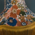 Une Baladeuse Jaune vibrante, dotée d'un abat-jour floral coloré avec un motif orné et orné d'une frange Jaune gaie. Brocante 93