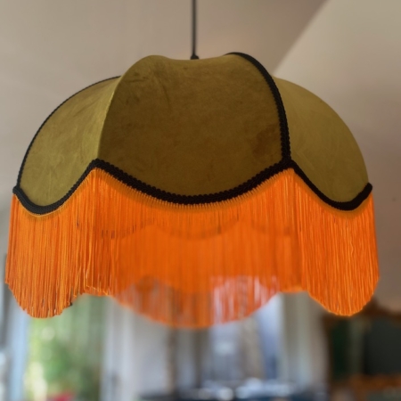 La lampe Suspension Dome Velours Kaki, dotée d'un design de style rétro avec un abat-jour en velours vert olive et de longs détails de franges orange, ajoute une touche d'élégance à n'importe quelle pièce. Brocante 93