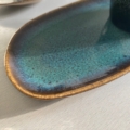 Une assiette en céramique turquoise avec un bord marron repose gracieusement sur une surface claire à côté de Duo tasses à café & plateau. Brocante 93