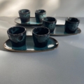 Six tasses à café et plateau Duo aux tons bleus et noirs avec des ombres projetées par la lumière du soleil. Brocante 93