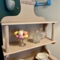 Le Vaisselier 1940 USA présente avec élégance une étagère en bois avec des macarons pastel dans un plat en verre, flanqué de pots en cristal et de bols méticuleusement étiquetés, incarnant l'esthétique classique des États-Unis. Brocante 93