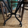 Les chaises Table Bistrot 1950, avec leurs élégants pieds courbés en métal, reposent gracieusement sur le plancher en bois, capturant une charmante ambiance des années 1950 lorsqu'elles sont vues d'en bas. Brocante 93