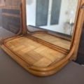 Le Miroir & Etagère Bambou 1960 présente un cadre en bois et une base à motifs en bois tressé, reflétant un arrière-plan intérieur flou. Brocante 93