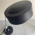 La Lampe Administrative 1960, une lampe de bureau noire moderne au design des années 60, présente un abat-jour et une base ronds, reposant élégamment sur une surface grise. Brocante 93